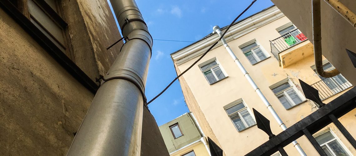 Saint-Petersburg architecture. Typical view of old buildings, drainpipe and fence against blue sky closeup