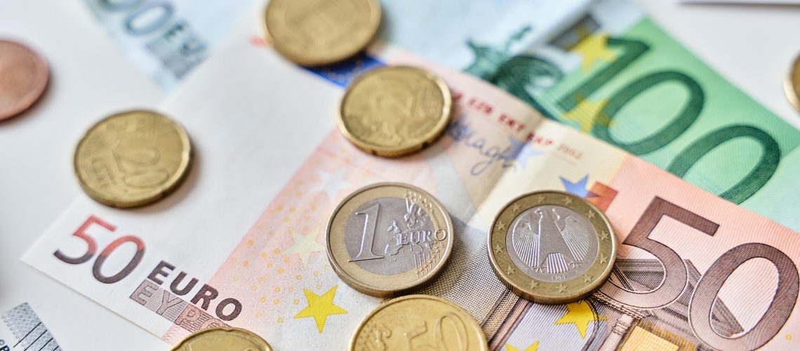Calculation of expenses. Close up of one euro coin surrounded by different coins and 100 and 50 Euro banknotes