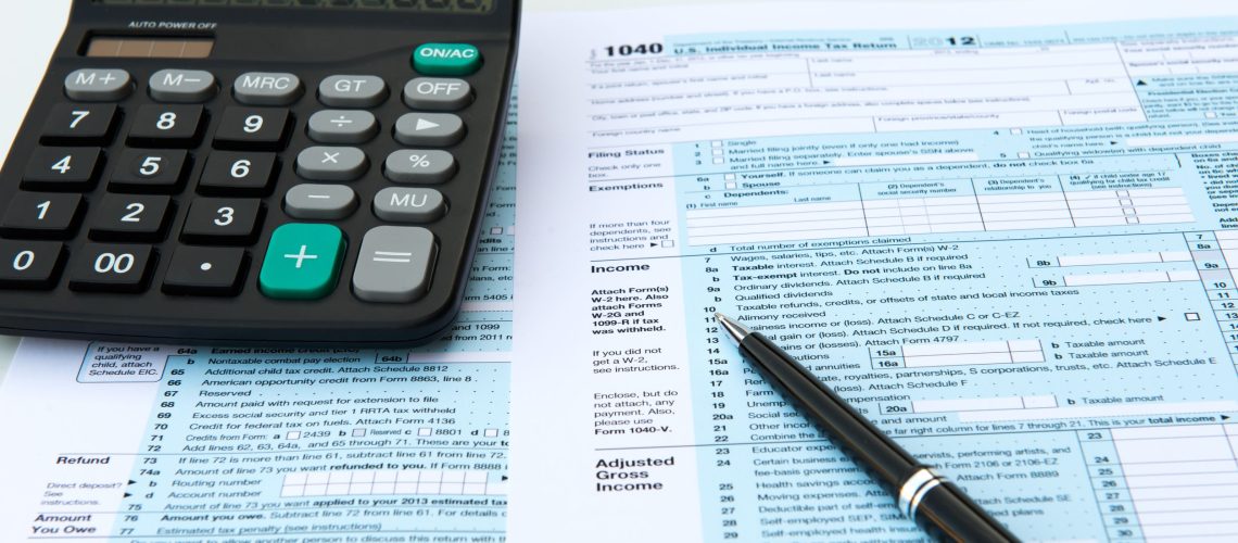 18262723 - filling out income tax forms with calculator and pen