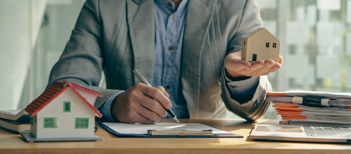 A real estate agent or bank officer explains the interest on the loan to the customer with a home purchase contract or insurance in the home office.