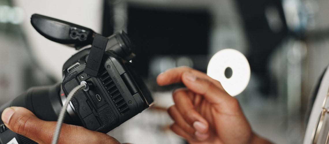 Man, hands and photographer with camera for production, film making or photoshoot at studio. Closeup, male person or producer working with screen or lens for content creation or media at workplace.