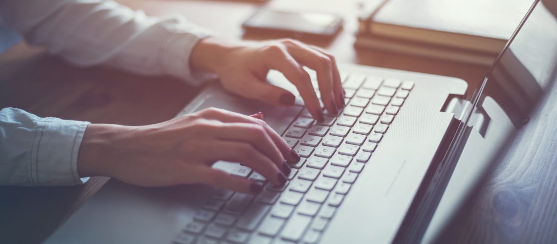 Working at home with laptop woman writing a blog. Female hands on the keyboard.